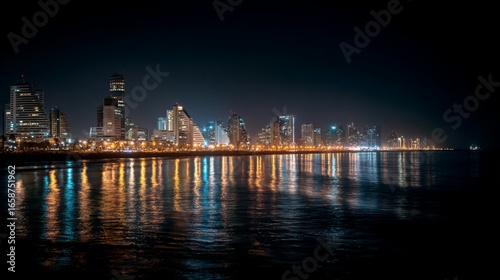 City skyline illuminated by night lights with reflections on water in a coastal location