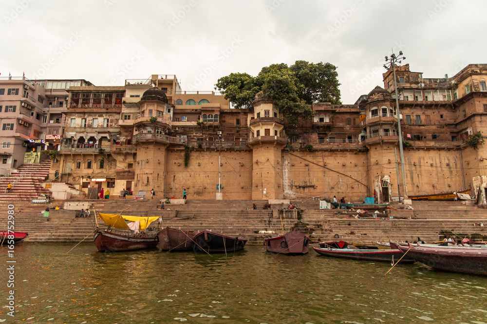 Naklejka premium Wooden Boats Floating on Ganges River with Varanasi Ghats in Background