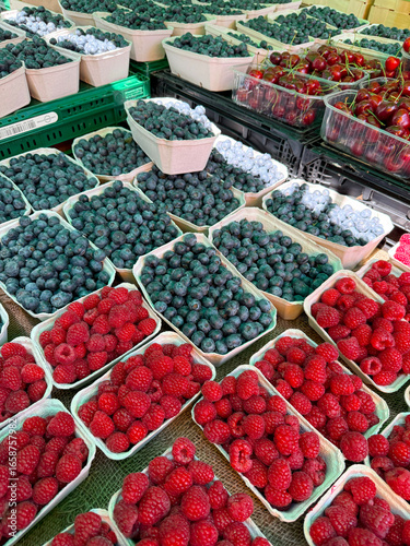 Fresh raspberries, blueberries and cherries displayed at a market stall