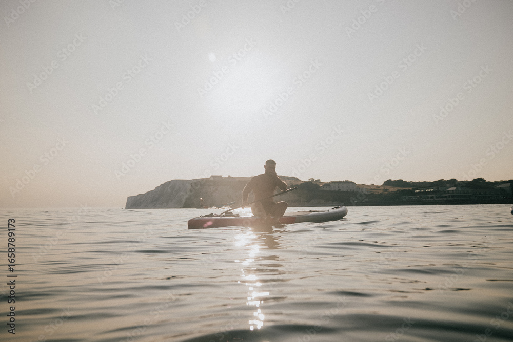 Fototapeta premium A man is sitting on a surfboard in the ocean