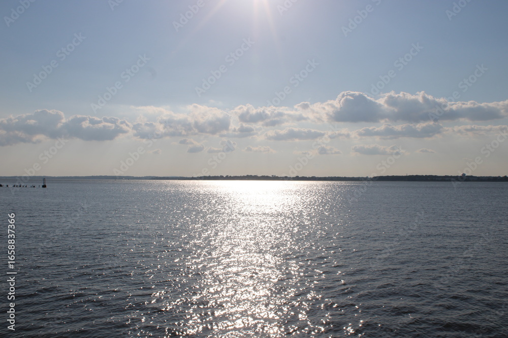 Fototapeta premium Breathtaking View of Shimmering Water Reflecting Sunlight With Distant Clouds Over the Horizon During a Tranquil Afternoon