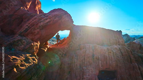 фотографія Red Rock Arch Formation with Hiker and Sun at Whitney Pocket Nevada