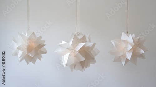 Three White Origami Star Lanterns Suspended Against a Neutral Wall Decoration