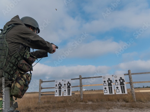 Tableau sur toile Military personnel aiming sidearm at shooting targets during tactical training s