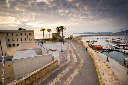 Quadro su tela pier in the sea, high view of the rampart promenade in Alghero at sunset with no people
