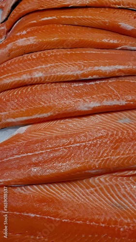 Several salmon fillets on ice at a fishmonger in Brazil_vertical.
