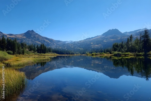 Clear blue sky over calm lake reflecting mountains.