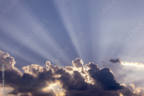 Canvas Print Dramatic sun rays breaking through dark clouds in the sky