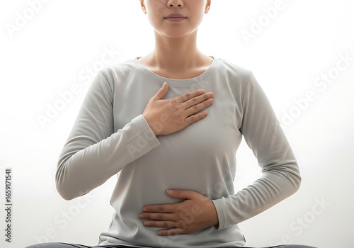 Young woman practicing mindful breathing with hands on chest and abdomen in bright studio for stress relief and relaxation.