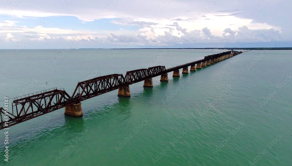 Obraz premium Aerial view of a rusty bridge over teal water