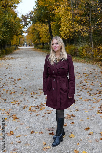 Woman Standing in Leafy Walkway During Autumn
