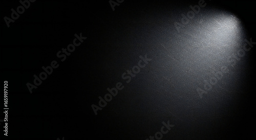 A single white spotlight beam shining down from the top right corner onto a dark textured background.