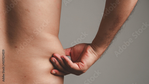 Photos Close-up of a man's hand pinching belly fat on his side