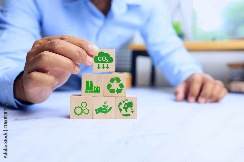 Obraz premium carbon dioxide reduction concept with a man arrange wooden block to reduce co2 emission carbon footprint and csr or corporate social responsibility activity, such as plant a tree to net zero