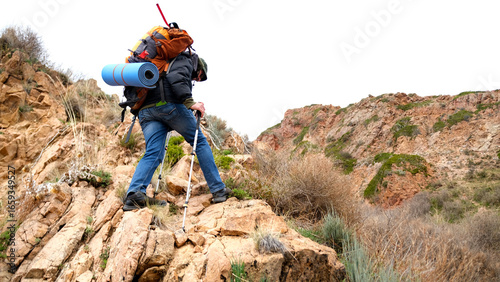 A lone traveler with a backpack climbs to the top of the mountain. The concept of adventure and determination