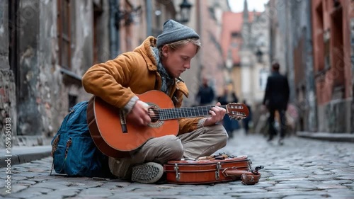 Melody on the Cobblestones: A street musician sits on a cobblestone street, playing his guitar, a worn case at his side, while people walk by in the background.