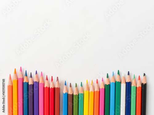 Colorful pencil crayons arranged in a wave on white background  