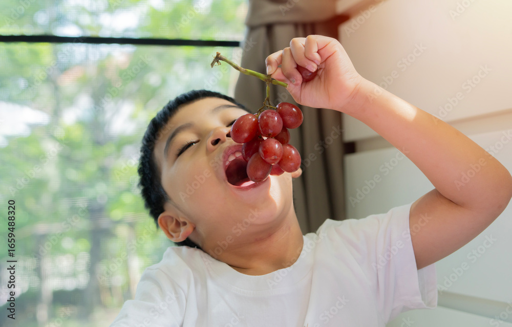 Obraz premium A child tasting a cotton candy grape with a delighted expression at home.