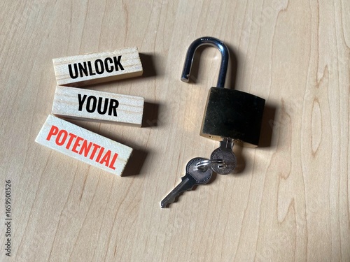 Wooden blocks labeled with the inspirational message 'Unlock Your Potential', positioned next to an open padlock and keys.
