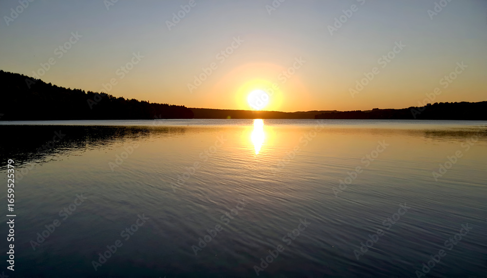 Naklejka premium Sunset over calm lake with serene nature.