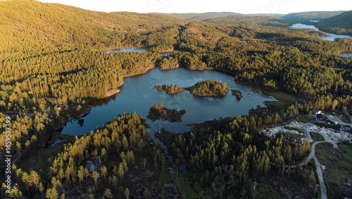 A turquoise lake in the middle of a forrest with small islands on it. Sunset in the evening. Norway (Mykland)