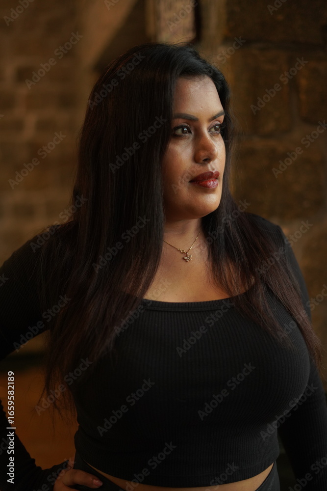 Fototapeta premium Confident Woman in Black Outfit Posing Indoors by Window