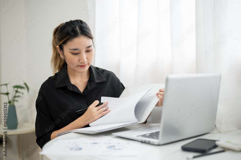 Fototapeta premium Smart asian businesswoman office worker holding pen reading document in file folder at working table