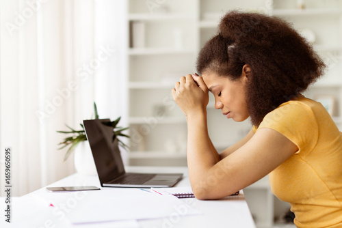 Tablou pe pânză Stressed African American woman sitting with closed eyes at desk with laptop