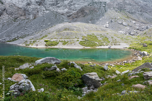 Shimmering emerald waters of Lake Volaia (Wolayersee) surrounded by alpine meadows and rocky slopes in the heart of the Carnic Alps on the Austrian-Italian border.