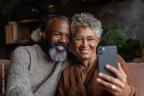 middle aged african couple sitting on a couch, expressive faces, looking at phone screen taking selfie or making video call