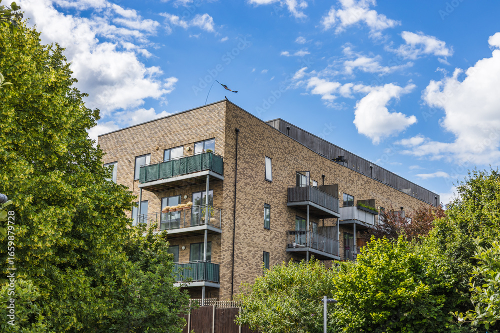 Fototapeta premium Contemporary residential brick building with balconies amid greenery