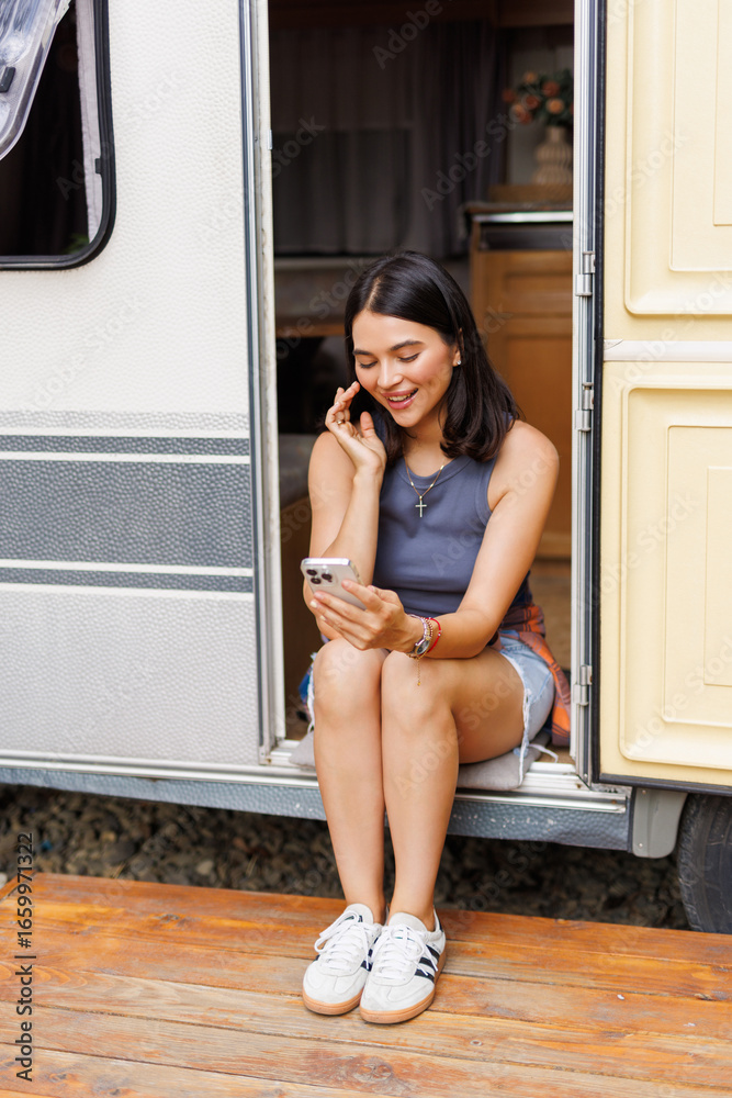 Obraz premium Young woman talking phone while sit in camper
