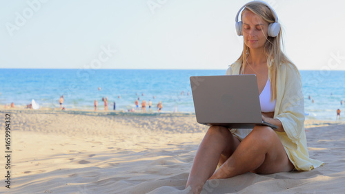 Woman working on laptop at the beach