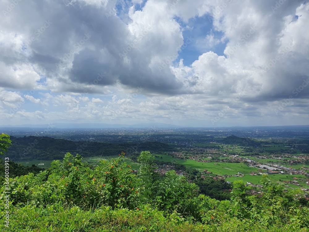 Obraz premium Lush green hills and cloudy horizon. Suitable for nature, travel, landscape, and environmental concepts. Perfect for backgrounds and marketing materials.