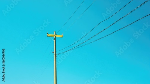 Numerous Birds Perched on a Yellow Telephone Pole Against a Bright Blue Sky During Daytime in Rural Setting with Overhead Power Lines