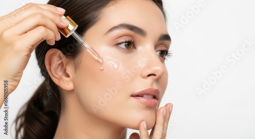 Radiant young woman meticulously applying a hydrating facial serum with a dropper, promoting glowing and healthy skin in her beauty routine