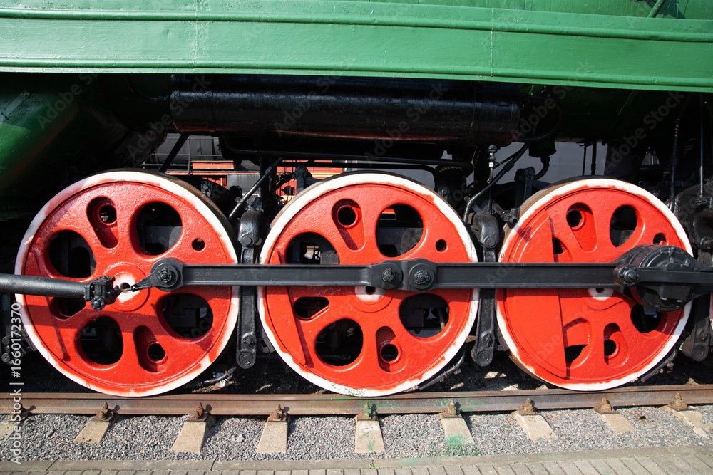 Naklejka premium Large metal wheels of a steam locomotive transmitting traction from the locomotive to the rails, industry, close-up