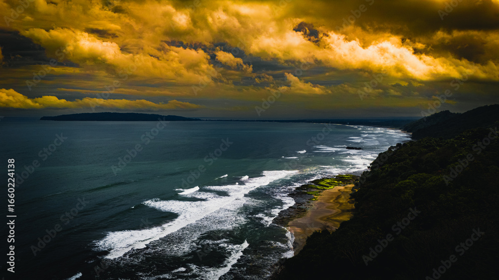 Fototapeta premium A moody coastal landscape featuring powerful waves crashing against the shore under a dramatic and stormy sky.