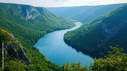 A breathtaking aerial view of a beautiful blue river flowing through a deep canyon, surrounded by a lush green landscape.