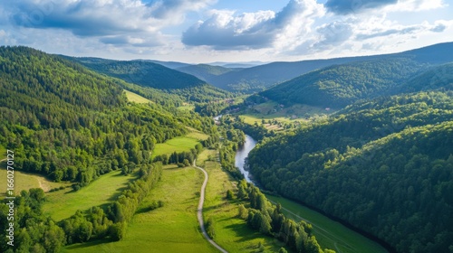 An aerial view of a winding river flowing through a lush green valley, surrounded by rolling hills and a serene natural landscape.