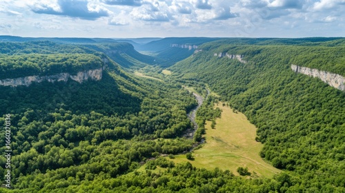 An aerial view of a winding river flowing through a beautiful and scenic landscape with green hills and valleys.