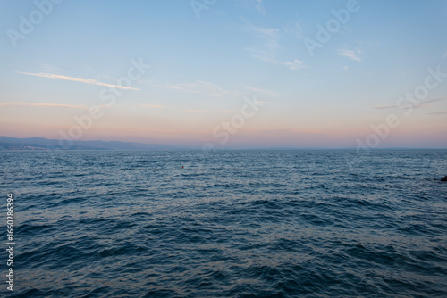 Fototapeta Naklejka Na Ścianę i Meble -  Minimalist photo of sea horizon and soft pastel sunset sky. Ideal for travel, mindfulness, and coastal lifestyle visuals. Scenic view of calm sea water and clear sky. Relaxing background for wellness,
