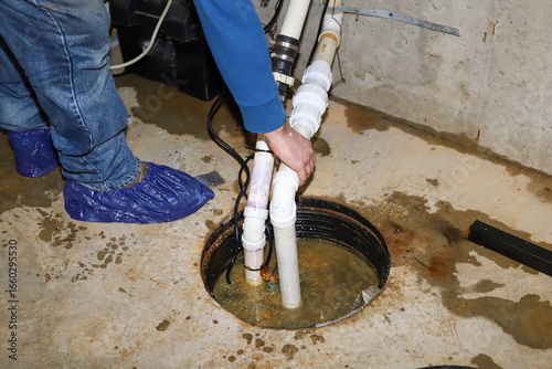   A plumber repairing a sump pump in a flooded basement in a residential home