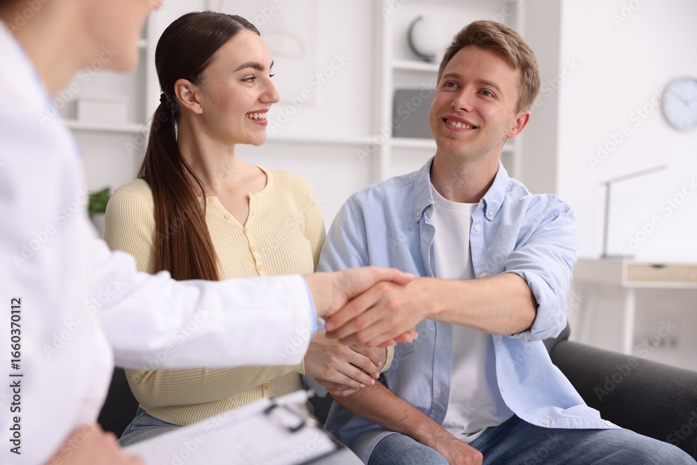 Fototapeta premium In vitro fertilization (IVF). Doctor shaking hands with couple in reproductive clinic