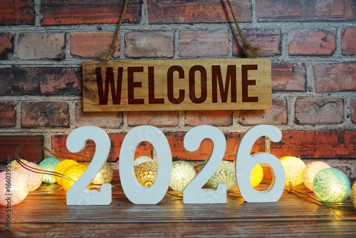 Welcome 2026 Happy New Year concept with LED cotton balls decoration on wooden background