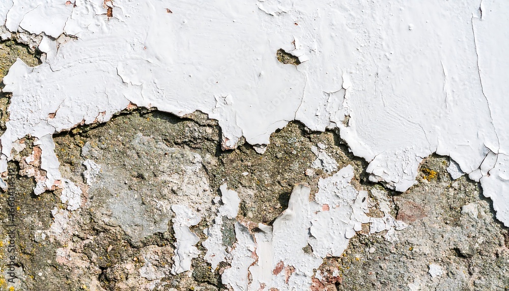 Obraz premium Peeling white paint reveals textured, aged gray stonework.