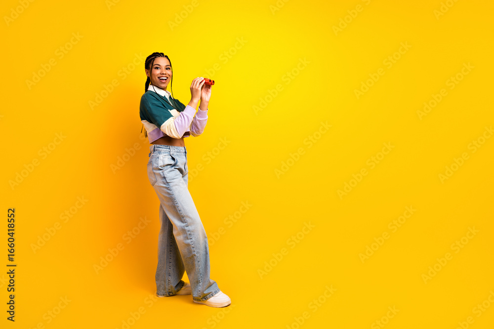 Fototapeta premium Happy young woman with playful gesture on bright yellow background demonstrating positivity and vibrant energy
