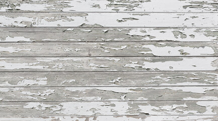 White paint peeling off wooden panels showing grey wood grain