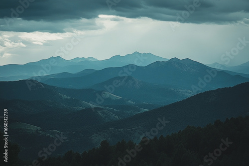 Serene Layers: Majestic Mountain Range Shrouded in Mystical Blue Hues Beneath Overcast Sky