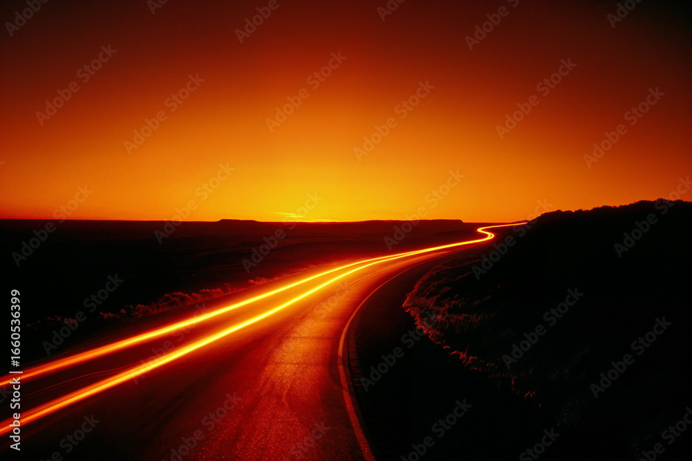 Naklejka premium Curved highway at sunset with headlight motion blur on road